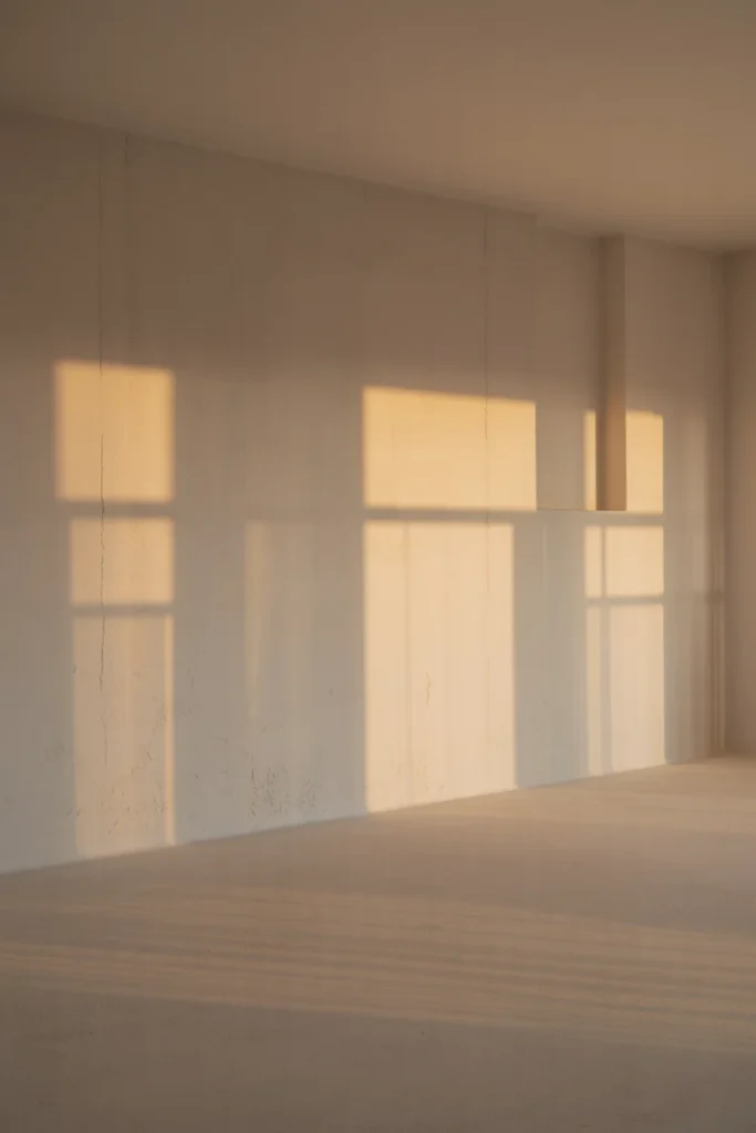 empty scandinavian wall with moving light and shadow patterns, ultra wide room perspective, angled sunlight creating gradients, close-up of subtle paint texture and imperfections, evening warm lighting variation, minimal interior, realistic photography style, 35mm lens