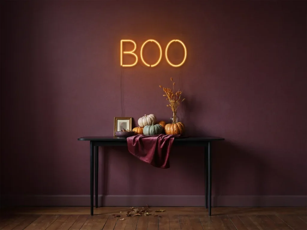 Spooky quote wall décor inspirations with a glowing amber Boo neon sign on a deep plum wall