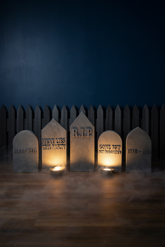 Foam tombstones and a black picket fence with low fog on a navy party wall