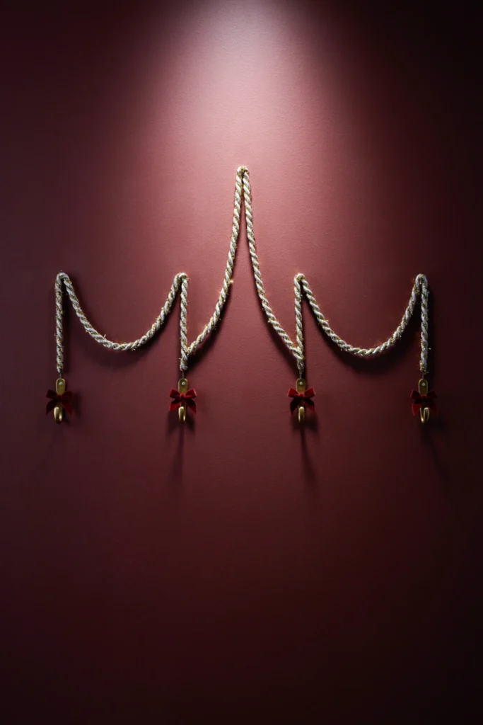 Silver and gold tinsel garland swagged in three scallops on a deep burgundy wall