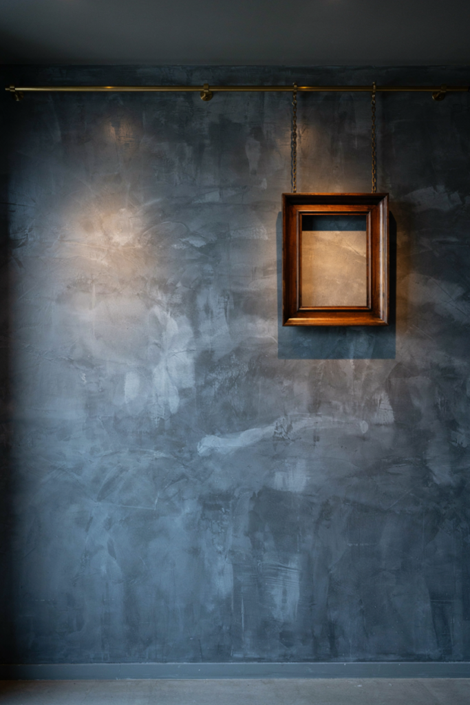 Slate polished plaster wall with a brass picture rail and a framed drawing on chains